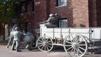 Rear-side view of the bronze sculpture of a horse-drawn wagon used by the fire brigade.