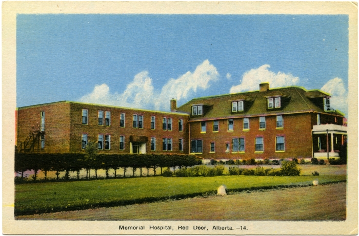 Colourized photo of the a two and three storey building, the Red Deer Municipal Hospital in Red Deer, Alberta in the 1940s. Shows an addition to the left side of the hospital.