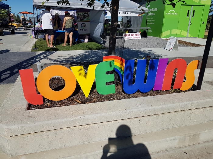 Coloured photo of a LOVE WINS sign on display at Pride in the Park in Capstone's Canada 150 Square in Red Deer
