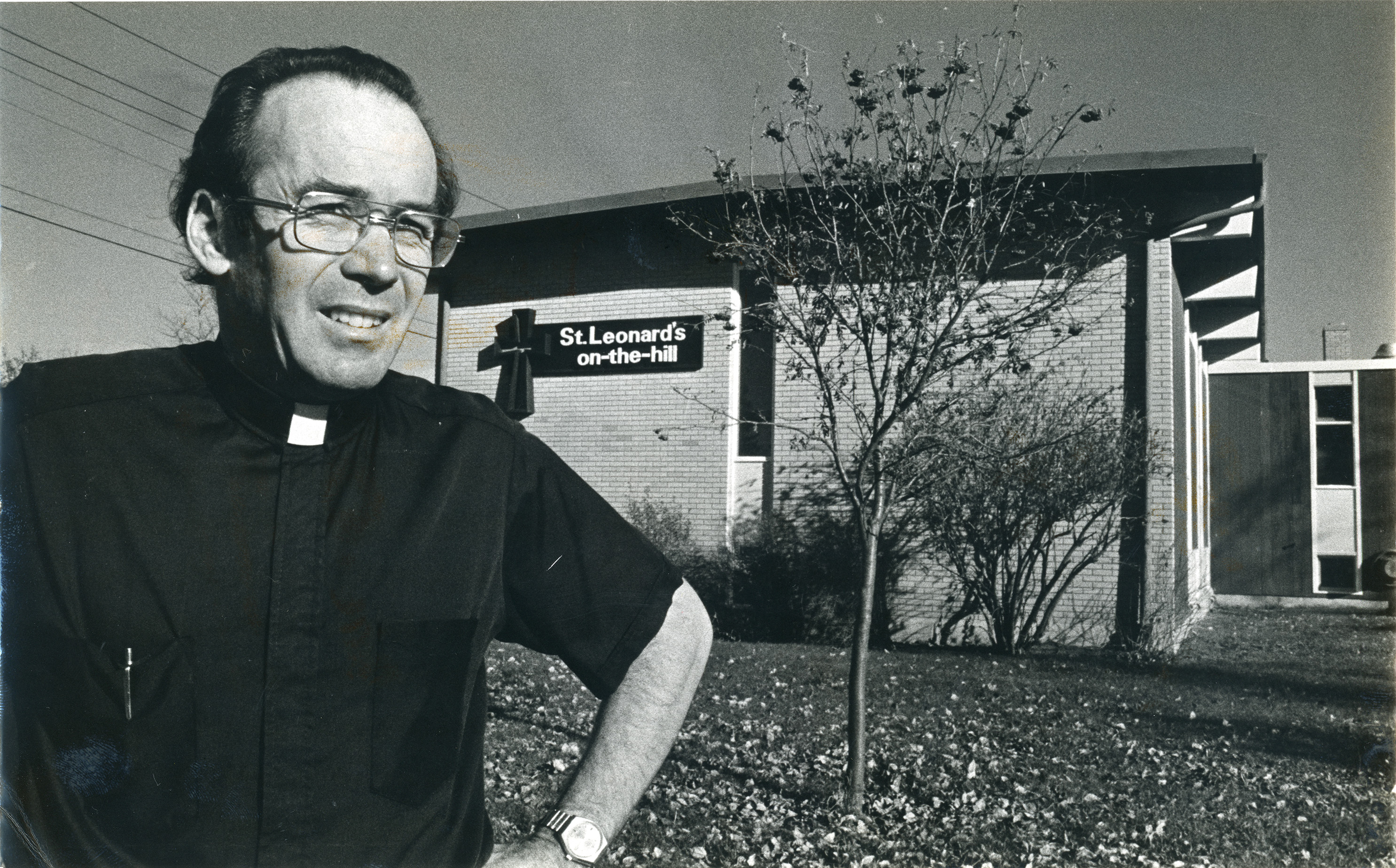 Black and white photo of Priest Terry Dunn standing outside St. Leonard's-on-the-Hill Anglican Church