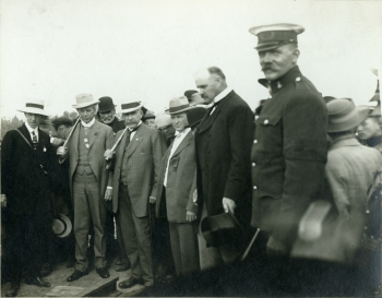 Black and white photo of a group of dignitaries driving the first spike in the Alberta Central Railway (ACR) track