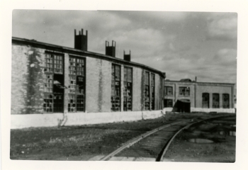Black and white photo of the old Canadian Pacific Railway (CPR) roundhouse in Red Deer with railroad tracks in front of it