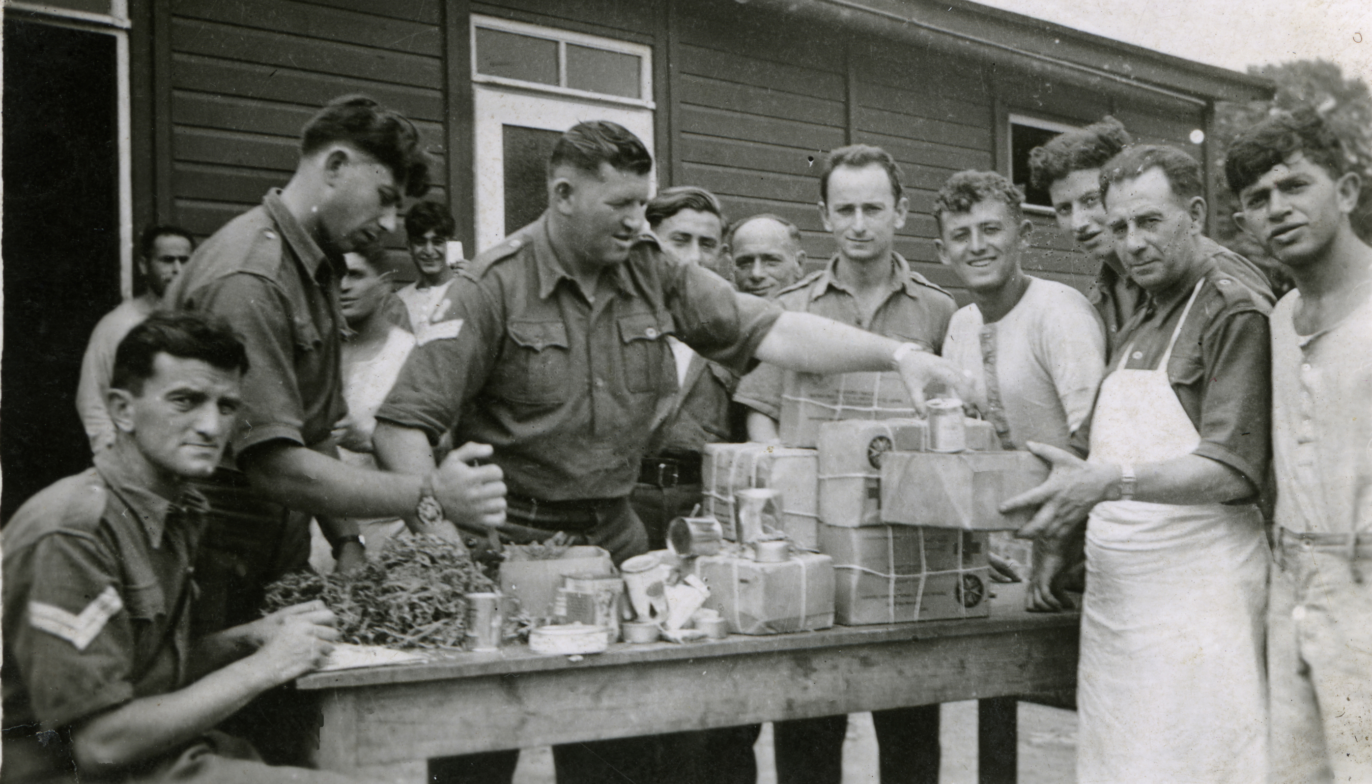 Black and white photo of a group of prisoners of war in Europe during the Second World War receiving Red Cross care packages