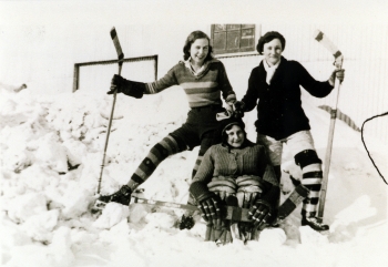 Helen Hayhoe, Marjorie Marshall, and Evie Nichols-Jenner of the Red Deer Amazon women's hockey team members sitting on snow