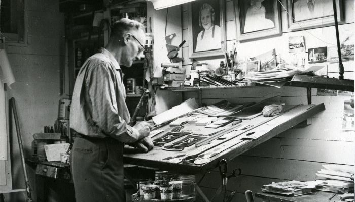 Black and white photo of Willard Trimble at his work table at Trimble's Signs in Red Deer