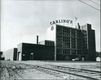 Black and white photo of the Carling's Brewery building with the railroad tracks in front of it
