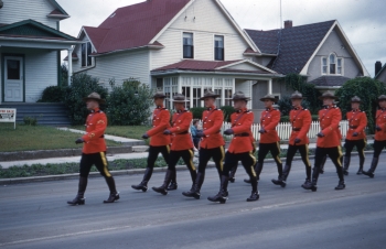 Coloured photo of RCMP officers marching in a parade in Red Deer in full dress