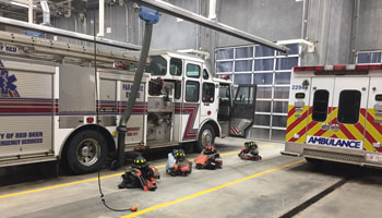 Fire truck and ambulance parked in station with equipment laid out for firefighters