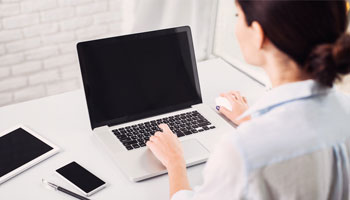 woman sitting in front of laptop using the mouse and keyboard