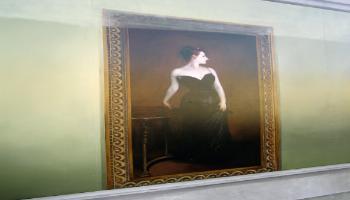 Painted mural of a framed painting of a slim woman standing beside a round table in a long black evening dress.