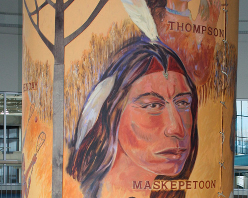 Close up of a painted canvas depicting aboriginal life. Portrait of a Maskepetoon.